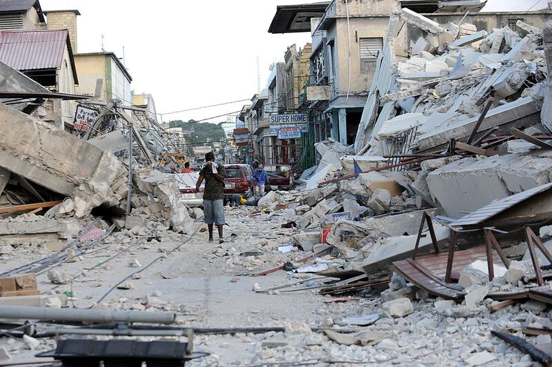 (FILES) In this file photo taken on January 14, 2010 a man covers his face as he walks amid the rubble of a destroyed building in Port-au-Prince on January 14, 2010, following the devastating earthquake that rocked Haiti on January 12. 
The British Government announced late Friday it was reviewing all work with Oxfam amid revelations the charity's staff hired prostitutes in Haiti during a 2011 relief effort on the earthquake-hit island. / AFP PHOTO / Juan BARRETO