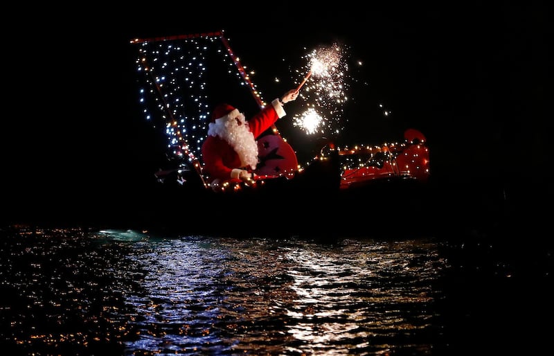 A man dressed as Santa Claus holds a flare as he sits on a boat during a Christmas eve celebrations in Imperia, Italy. AP