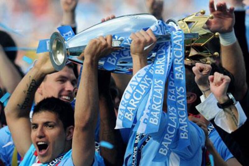 Sergio Aguero, bottom left, scorer of the title match-winning goal for Manchester City, celebrates with the trophy after the Queens Park Rangers game. Manager Roberto Mancini says keeping their hands on that trophy this season, as well as winning any other silverware, will be harder.