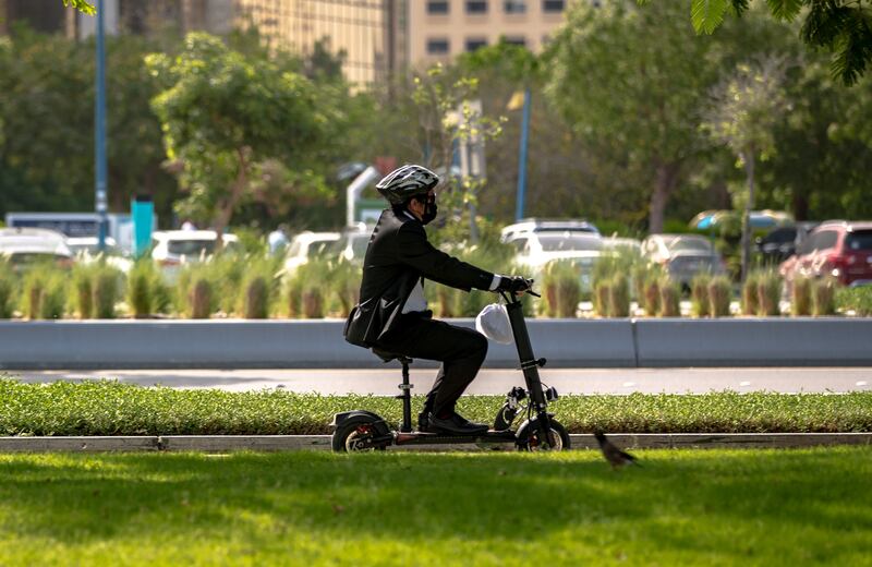 A man rides his e-scooter to work in the morning along the Corniche, Abu Dhabi on May 5th, 2021. Victor Besa / The National.