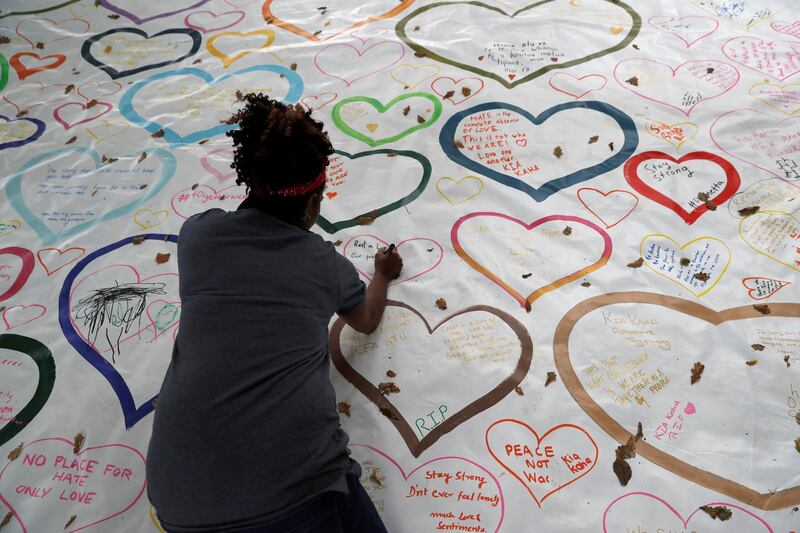 People write on a sign at a memorial as a tribute to victims of the mosque attacks, near a police line outside Al Noor mosque in Christchurch, New Zealand. Reuters