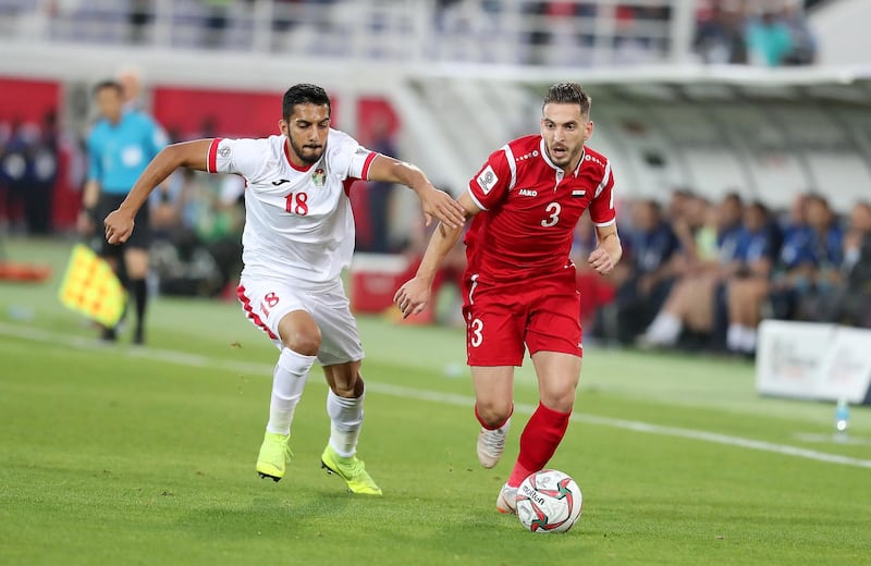 AL AIN , UNITED ARAB EMIRATES , January 10 ��� 2019 :- Mousa Mohammad Suleiman ( no 18 in white ) of Jordan and Mouaiad Alajaan (  no 3 in red ) of Syria in action during the AFC Asian Cup UAE 2019 football match between Jordan vs Syria held at Sheikh Khalifa International Stadium in Al Ain. ( Pawan Singh / The National ) For News/Sports/Instagram. Story by Amith