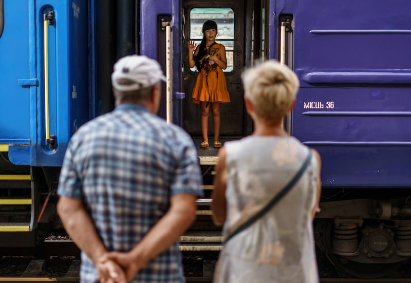 A young girl with her dog waves goodbye to her grandparents from an evacuation train leaving Pokrovsk in August 2022