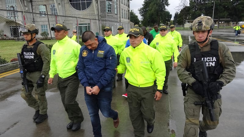 FILE - This undated photo released by Colombia's National Police show officers escorting a man who police identify as Ecuadorean drug trafficker Washington Edison Prado after his April 2017 arrest on an indictment by a Florida federal court. Colombiaâ€™s chief prosecutorâ€™s office said Saturday, Feb. 24. 2018, that it has extradited Prado to the United States. (Colombia National Police via AP, File)