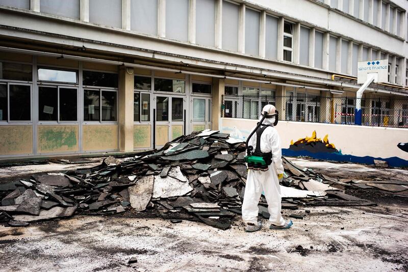 A worker stands next to asphalt waste materials as he takes part in a clean-up operation at Saint Benoit school. AFP