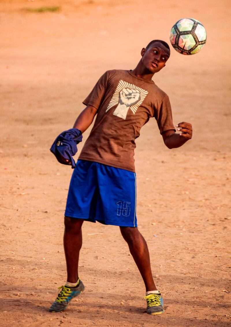 A Sudanese youth plays with a football on a dirt field in the capital Khartoum.