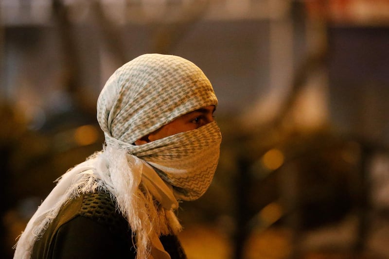 A Palestinian youth wearing a mask looks on during clashes with  Israeli security forces in the city center of the occupied West Bank town of Hebron, following a protest in support of Palestinian demonstration in Israeli-annexed east Jerusalem. AFP