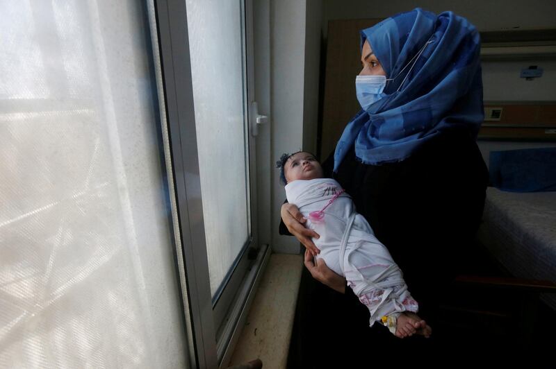 An Iraqi woman wearing a protective mask carries her baby who suffers from cancer at the Children's Hospital for Cancer Diseases, amid the spread of the coronavirus disease in Basra. Reuters