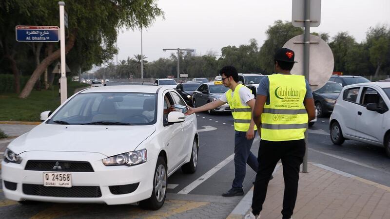 Emirates Red Crescent volunteers distribute iftar boxes and water to motorists waiting at red lights in the Mushrif area of Abu Dhabi in 2018. The National  