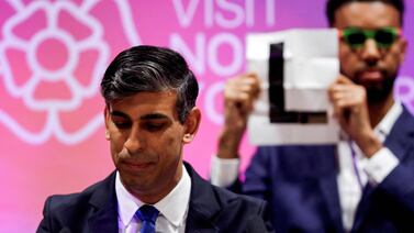 Independent candidate Niko Omilana (back) holds an 'L' sign behind Britain's Prime Minister and Conservative Party leader Rishi Sunak as he delivers a speech after retaining his seat as MP for Richmond and Northallerton in the north of England. AFP