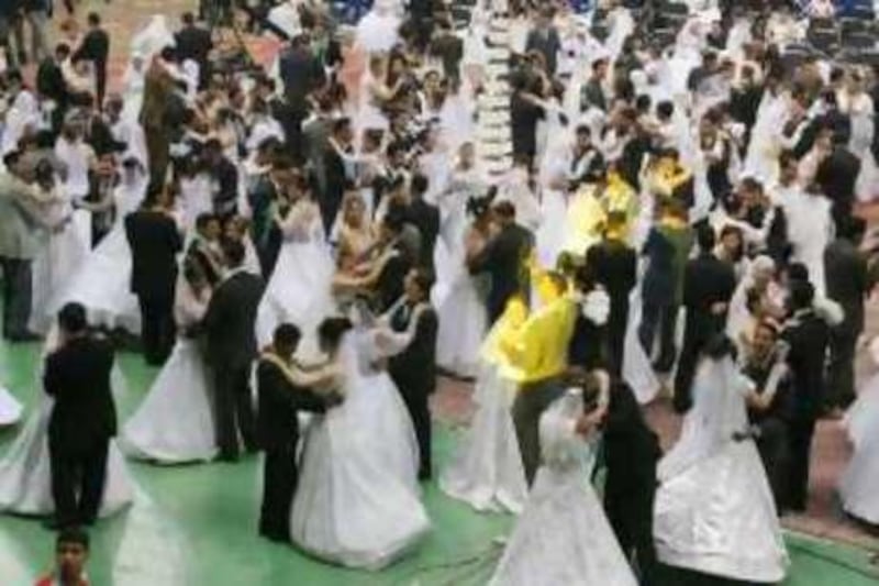 Newly married couples dance at the Cairo International Stadium in Cairo, Egypt Thursday, April 6, 2006. Five hundred Egyptian couples celebrated a mass wedding sponsored by charity organizations to reduce the high cost of this ceremony while families and friends shared this event with them from the Stadium's grandstand.  (AP Photo/Nasser Nasser)