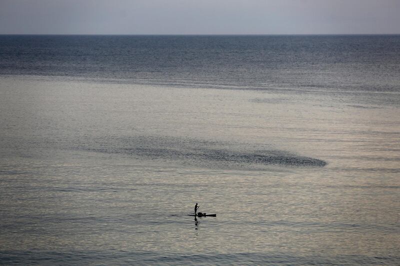 A man stands on his surf on Beirut's Mediterranean Sea an hour before the starting of the nighttime curfew that imposed by the government to help stem the spread of coronavirus, Lebanon. AP Photo