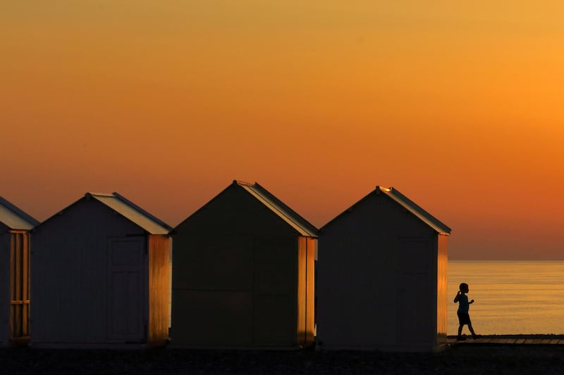 A child walks beside beach cabins on a pebbled beach, during sunset as a heatwave hits France, in Cayeux-sur-Mer, France.  Reuters