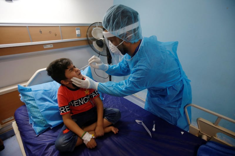 A health worker takes a swab sample from a child who suffers from cancer for Covid-19 testing, at the Children's Hospital for Cancer Diseases in Basra, Iraq. Reuters