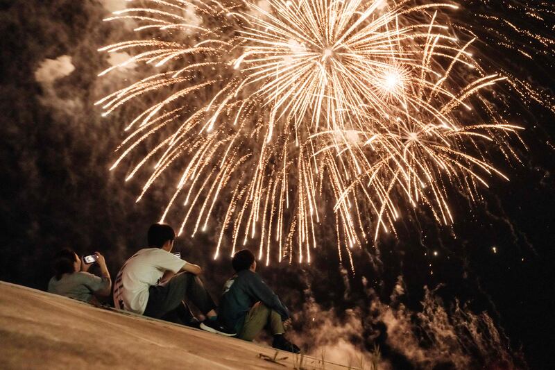 People watch the fireworks from the seawall in Minamisoma, Fukushima, reconstructed after the tsunami in 2011. The display was not announced officially to avoid major crowds of spectators turning up as Japan hosts the Tokyo Olympic Games during the Covid-19 health crisis.