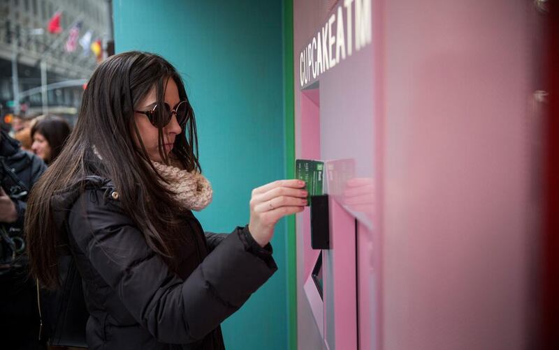 A woman swipes her card at the Cupcake ATM.