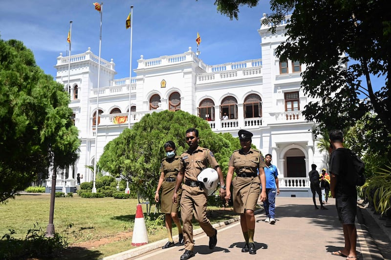 Police officers walk outside Sri Lankan Prime Minister Ranil Wickremesinghe's office, a day after thousands of anti-government protesters stormed the building, when he was named acting president. AFP