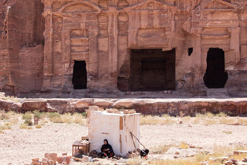 A Bedouin woman selling tea waits for customers at the reopened Petra archeological site, in Jordan. EPA