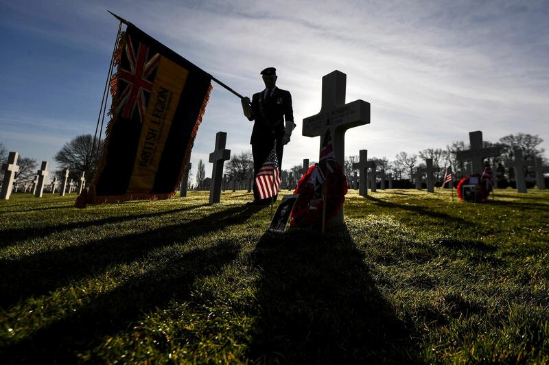John McCarthy from the Royal British Legion pays his respects at the grave of Sergeant Maurice Robbins at the Cambridge American Cemetery in Coton, England. PA via AP