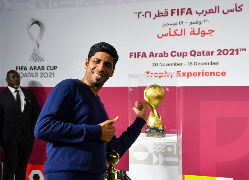 A man poses next to the Fifa Arab Cup Trophy.