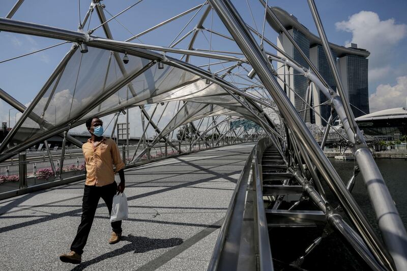 A man wearing a surgical mask walks along the Helix Bridge next to the Marina Bay Sands hotel in Singapore.  EPA