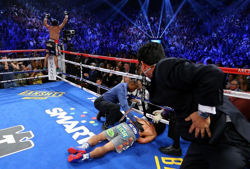 LAS VEGAS, NV - DECEMBER 08: Manny Pacquiao lays face down on the mat after being knocked out in the sixth round as Juan Manuel Marquez celebrates during their welterweight bout at the MGM Grand Garden Arena on December 8, 2012 in Las Vegas, Nevada.   Al Bello/Getty Images/AFP== FOR NEWSPAPERS, INTERNET, TELCOS & TELEVISION USE ONLY ==
 *** Local Caption ***  064445-01-09.jpg