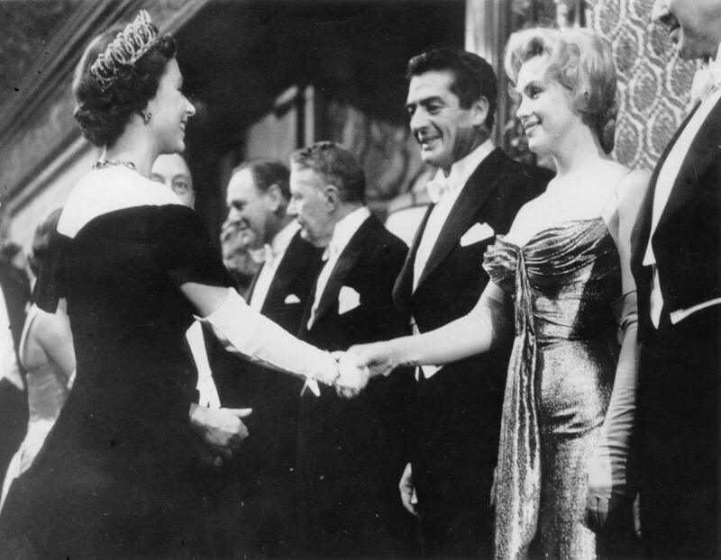 US actress Marilyn Monroe and actor Victor Mature meet the British monarch at the Empire Theatre in London. Getty