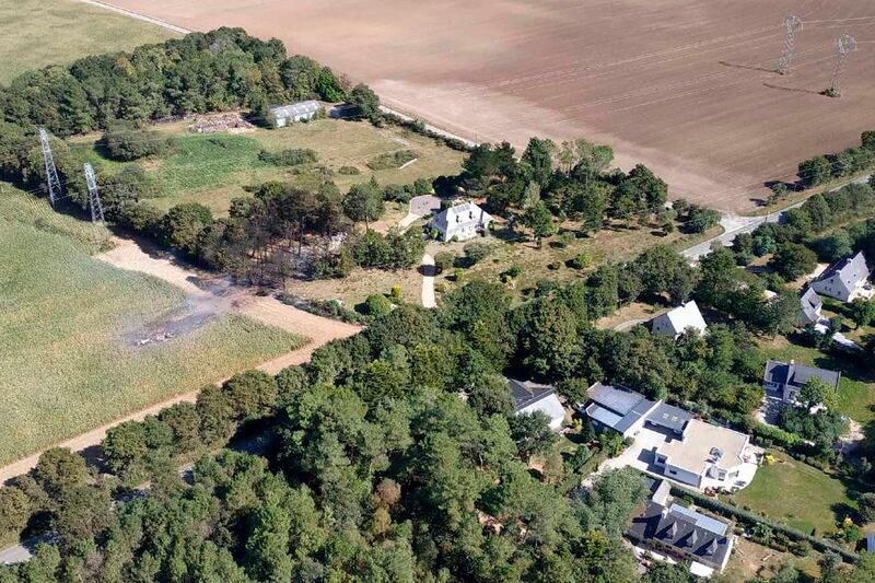 This photo provided by the Morbihan Prefecture shows the crash site of F16 jet fighter, Thursday, Sept.19, 2019 in Pluvigner, western France. A Belgian F-16 fighter jet crashed in western France, damaging a house, setting a field ablaze and leaving one of the two pilots dangling by his parachute from a high-voltage electricity line for two hours, French authorities said. (Prefecture du Morbihan via AP)
