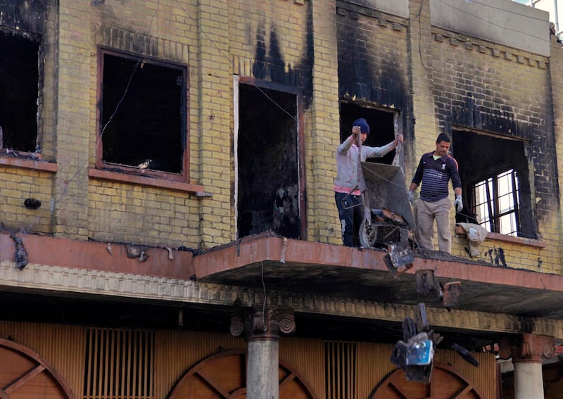 Shops owners throw out their burnt goods while cleaning their shops after clashes between security forces and anti-government protesters in Rasheed Street. AP