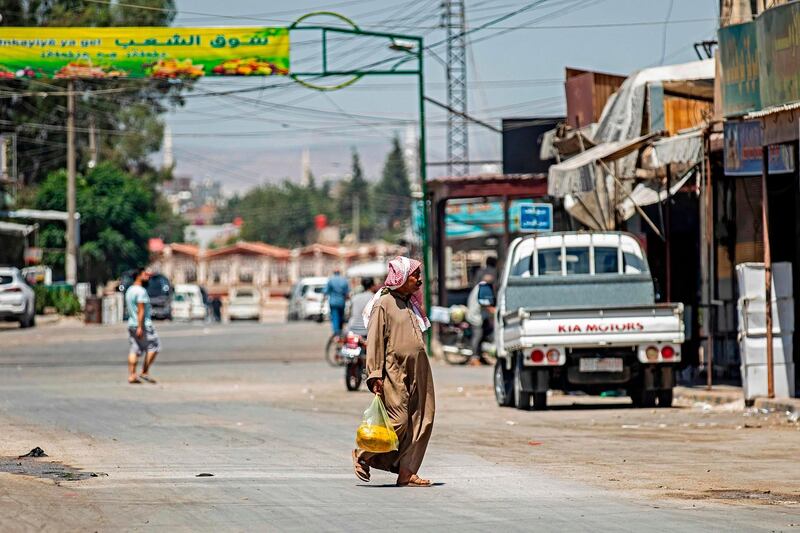 A few pedestrians walk in an almost deserted street in the Kurdish-majority city of Qamishli of Syria's northeastern Hasakeh province, during a lockdown due to surging cases of Covid-19 infections. AFP