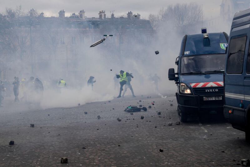 Protesters throw a scooter and stones at riot police in Paris on March 16, 2019, as the 'Yellow Vest' (gilets jaunes) movement entered its 18th consecutive week of nationwide protests against the French president's policies and style of governing, the high cost of living, tax reforms and to demand 'social and economic justice'. AFP