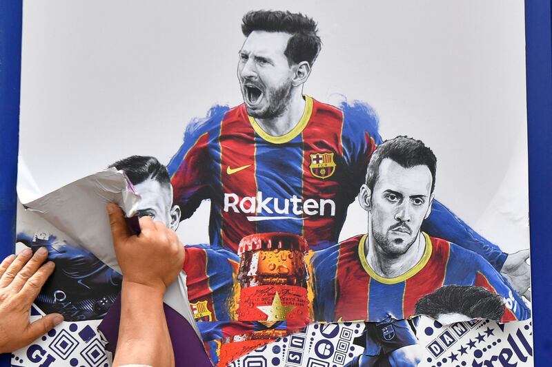 A worker removes posters featuring Barcelona's departing forward Lionel Messi at the Camp Nou.