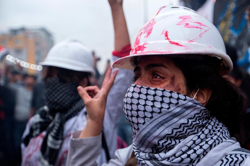 A demonstrator wearing a protective helmet flashes the victory sign in Tahrir Square. AFP