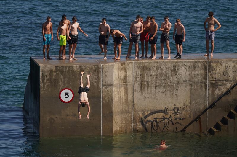 Men cool off by diving into the water at Cullercoats Bay in North Tyneside. AP