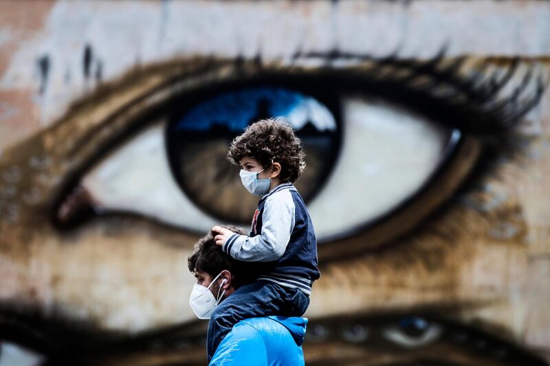 A man and a boy walk in front of a grafitti mural amid the ongoing pandemic in Rome. EPA