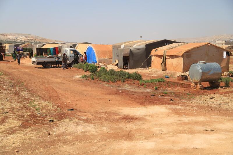 A picture of the worn and patchy camps in north Syria borders with Turkey showing a tank of drinking water provided in a camp.