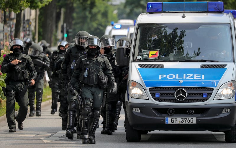 Members of a German riot police unit walk next to a police van.  Armando Babani / EPA