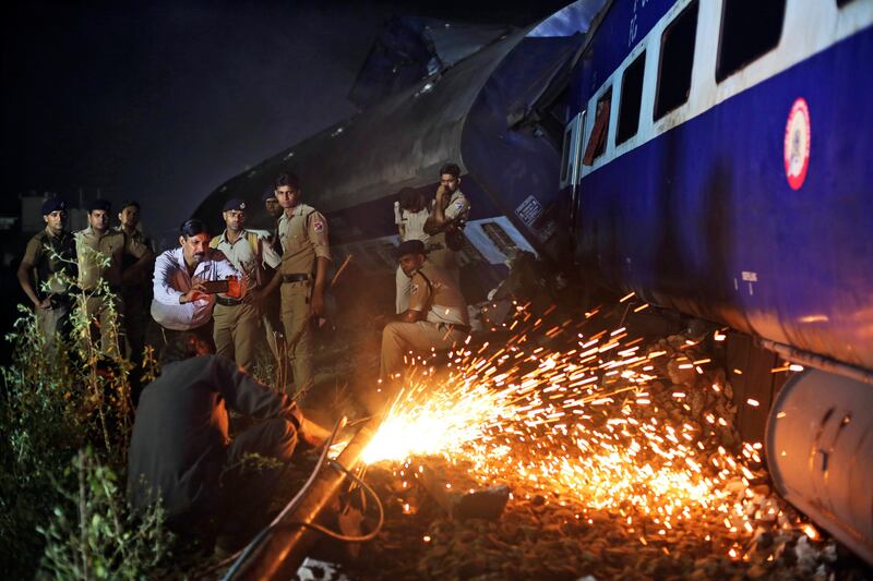 Indian police watch as rescue work is in progress near the upturned coaches of the Kalinga-Utkal Express. Altaf Qadri / The Associated Press