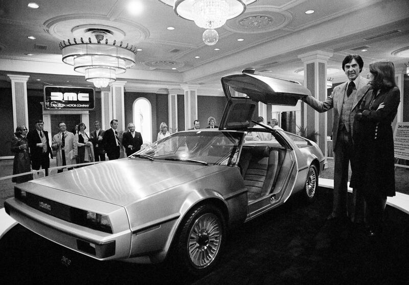 John DeLorean, left, and his wife Christina DeLorean, right, stand by DeLoreans prototype car, model 12 that was unveiled, Monday, Jan. 31, 1977, New Orleans, La. The brushed steel and fiber-glass sports car is scheduled for production in 1979 with a six-cylinder engine reported to get 30 miles per gallon on the highway. The cost: around $10,000. (AP Photo/Jack Thornell)
