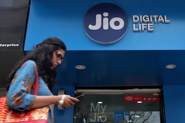 A woman checks her mobile phone as she walks past a Jio mobile store in Mumbai. Reuters.    