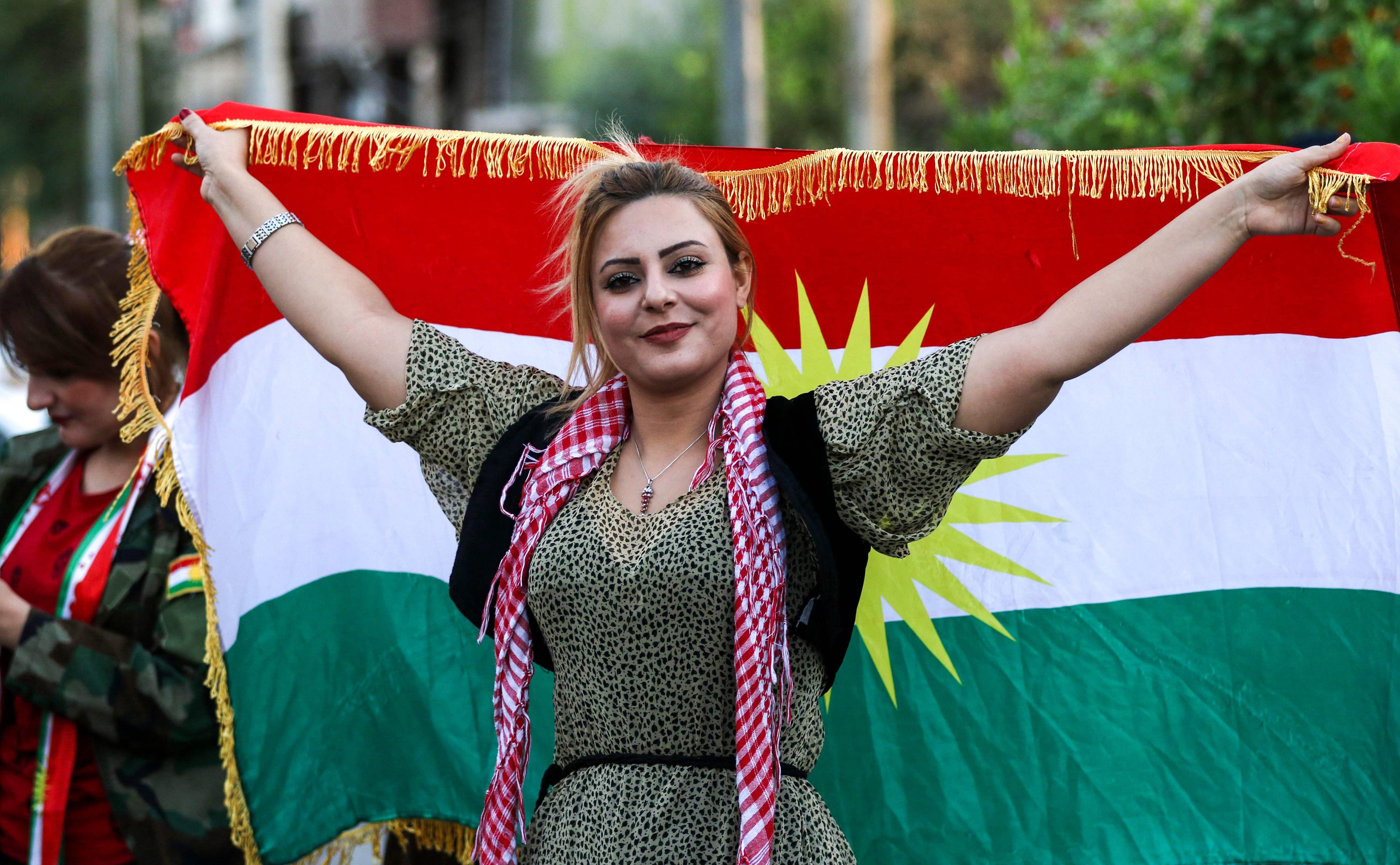 An Iraqi Kurdish woman poses with the flag of Iraqi Kurdistan during a demonstration outside the UN Office in Arbil, the capital of the autonomous region, on October 21, 2017, protesting against the escalating crisis with Baghdad. / AFP PHOTO / SAFIN HAMED