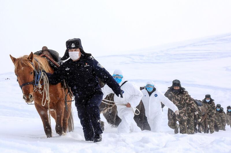 This photo taken on February 19, 2020 shows police officers wearing protective face masks walking with horses on their way to visit residents who live in remote areas in Altay, farwest China's Xinjiang region, to promote the awareness of the virus. The death toll from China's new coronavirus epidemic jumped to 2,112 on February 20 after 108 more people died in Hubei province, the hard-hit epicentre of the outbreak. - China OUT
 / AFP / STR
