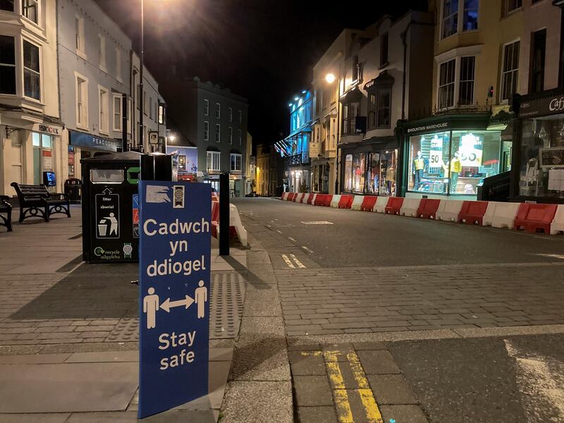 A social distancing sign is seen in an empty street during the first evening of the welsh lockdown, amid the coronavirus disease (COVID-19) outbreak, in Tenby, Wales, Britain October 23, 2020. REUTERS/Rebecca Naden