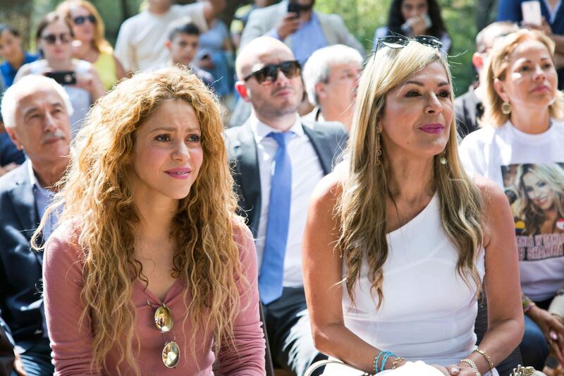 This Friday, July 13, 2018 photo provided by the Honorary Consulate of Lebanon in Barranquilla, Colombia, shows Colombian singer Shakira, left, sitting at a ceremony during her visit to Tannourine's Cedar Reserve, in the northern Lebanese mountain village of Tannourine. The singer planted a tree in the village where her paternal grandmother was born. She later performed a concert at the country's Cedars International Festival in front of thousands of fans. (Erick Deeb via AP)