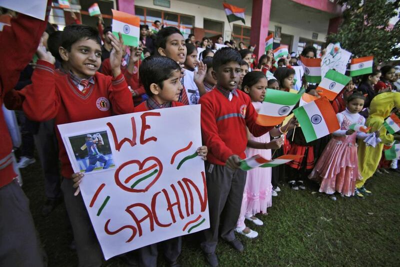 Indian school children wave Indian flags and display placards of Tendulkar as they gather to honour him in Jammu, India, Thursday. Channi Anand / AP