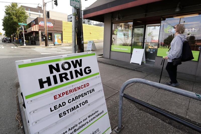FILE In this June 4, 2020 photo, a pedestrian wearing a mask walks past reader board advertising a job opening for a remodeling company, in Seattle. On Thursday, June 25, the number of laid-off workers who applied for unemployment benefits fell to 1.48 million last week, the 12th straight drop and a sign that layoffs are slowing but are still at a painfully high level. (AP Photo/Elaine Thompson, File)