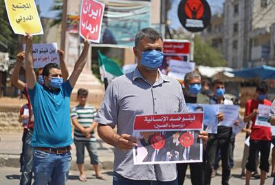 Syrian protesters in the city of Idlib carry placards expressing their opposition to regime ally Russia's attempt to reduce cross-border aid to millions in the northwest of the war-torn country, as they wear protective masks and maintain social distancing due to the first case of coronavirus recorded a day earlier, on July 10, 2020.  The Russian motion at the UN Security Council was voted down, but a council resolution authorising aid deliveries through the Turkish border expires today.  / AFP / Abdulaziz KETAZ
