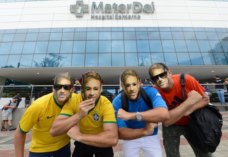 Supporters wear Neymar face masks as they pose for a photo outside the Mater Dei Hospital, where the soccer star will undergo surgery, in Belo Horizonte, Brazil, Saturday, March 3, 2018. Neymar will have surgery on a fractured toe in his right foot and could be out for up to three months, an estimate that would take the Brazil striker right up to the World Cup. (AP Photo/Eugenio Savio)