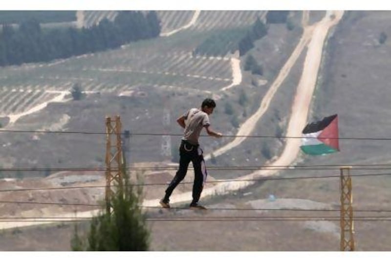 A man practices walking on ropes near a set flag at Iran Garden, the park developed by an Iranian organisation that faces an Israeli settlement, seen in the background, in the border village of Maroun el Rass, Lebanon. Mohammed Zaatari / AP Photo