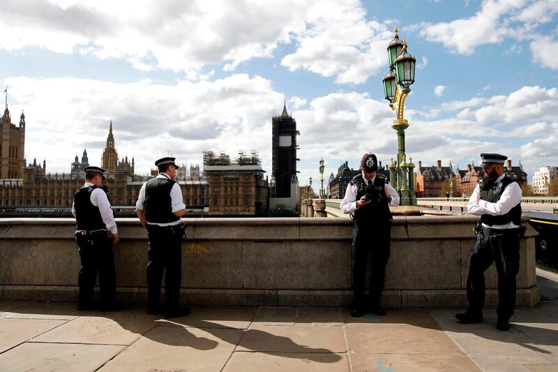 British police officers stand on duty, on the south side of Westminster Bridge, with the Houses of Parliament behind, in London as life in Britain continues during the nationwide lockdown to combat the novel coronavirus pandemic. AFP